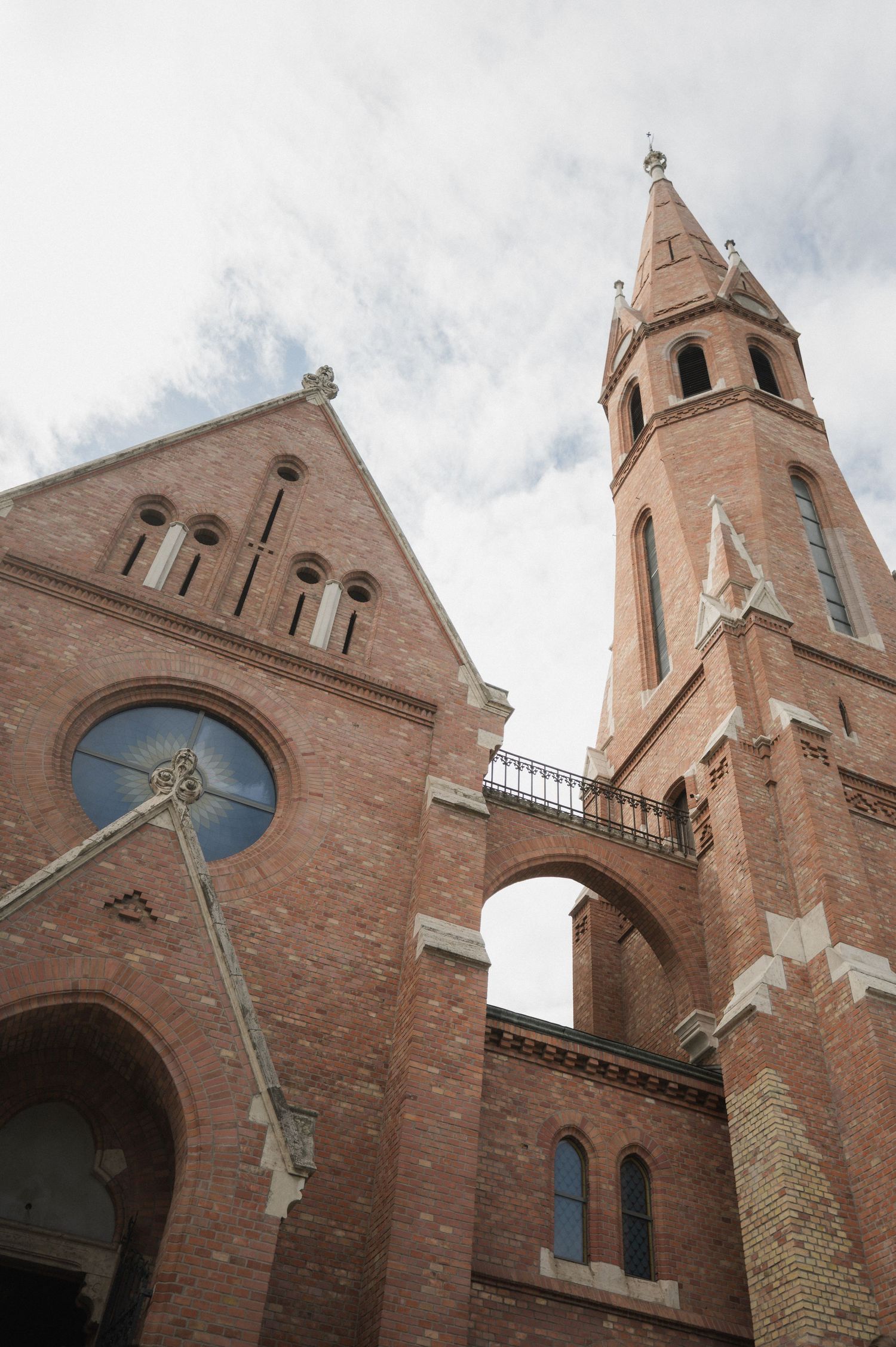 Exterior view of a tall red brick Gothic church with arched windows and a pointed bell tower.