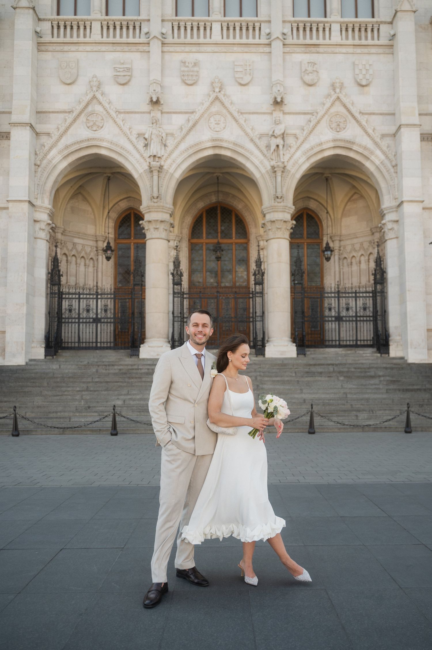 A wedding couple poses together against beautiful gothic church architecture.