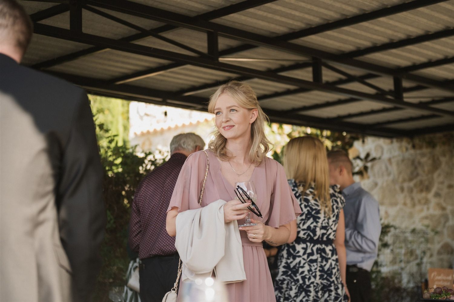 Wedding guests gather under a covered outdoor reception area.