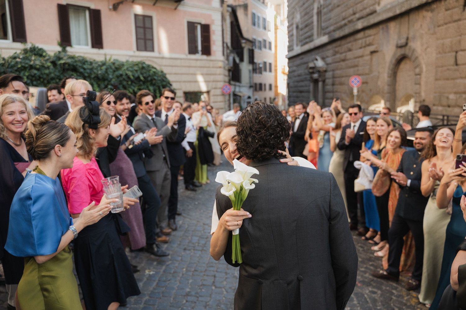 Wedding guests form a line on a charming Italian street to celebrate the newlyweds.