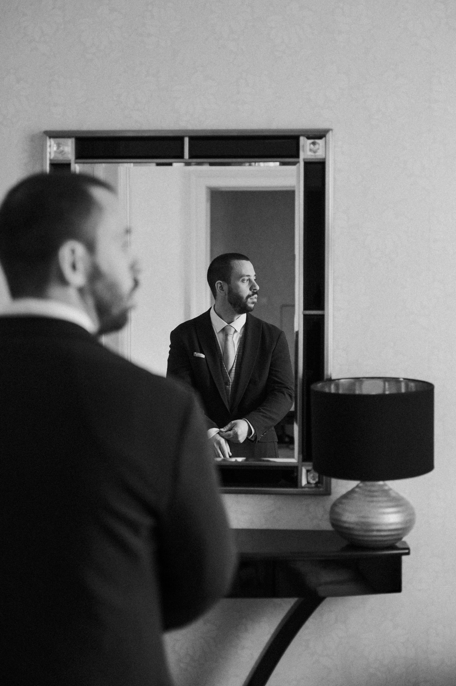 A black and white photo series shows a man in a suit reflected in multiple mirrors creating a surreal repetitive effect.