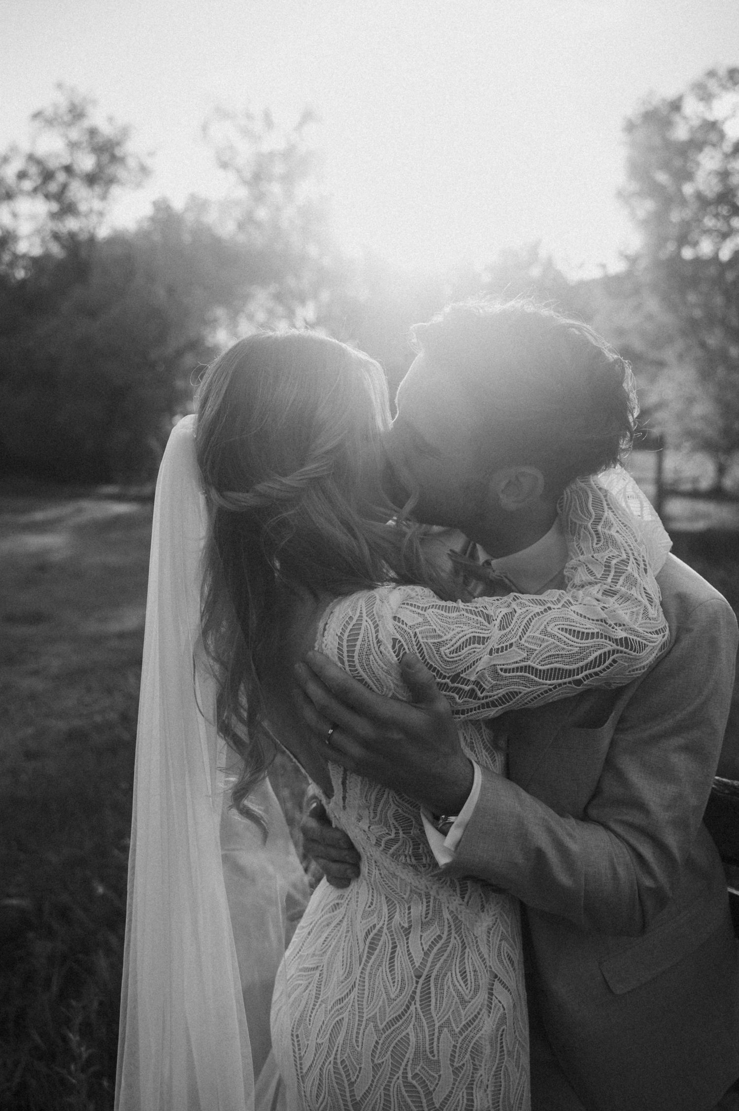 A romantic black and white photo sequence showing a tender embrace between a couple in a sunlit outdoor setting.
