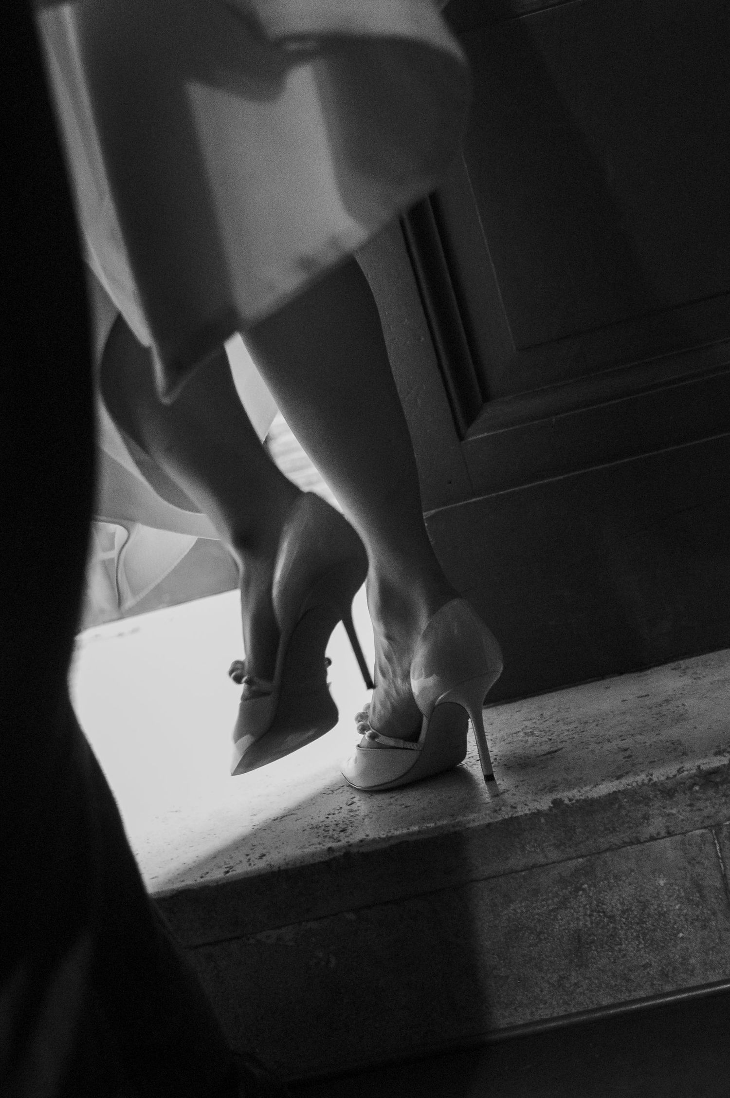 Artistic black and white photo of wedding dress hem and shoes.