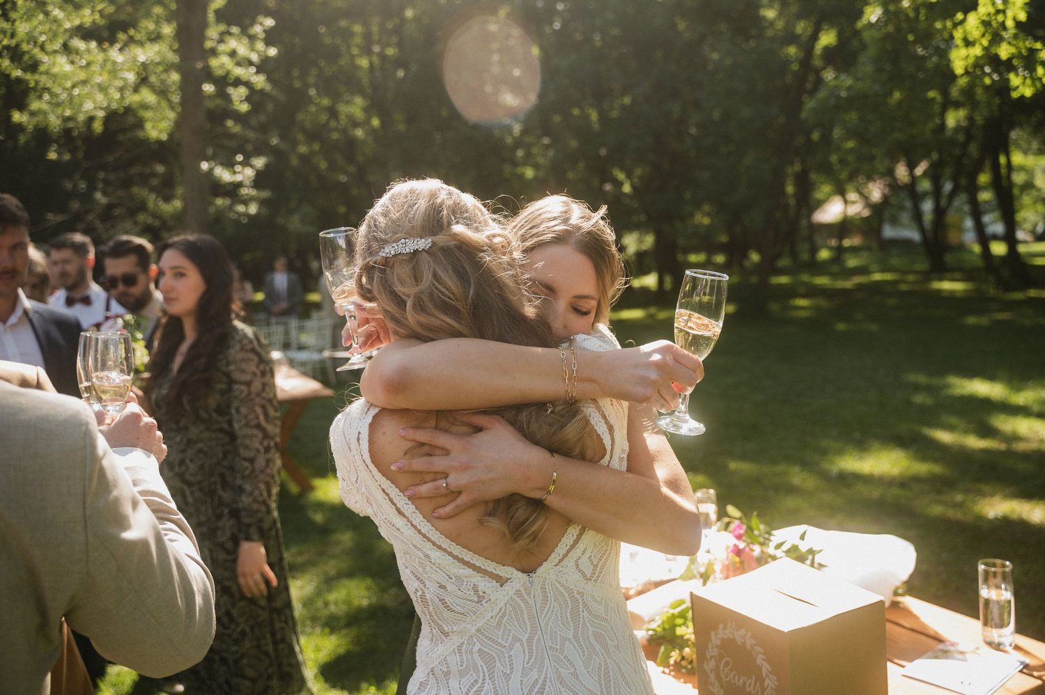 A couple embraces while dancing in a sunlit garden during an outdoor celebration.