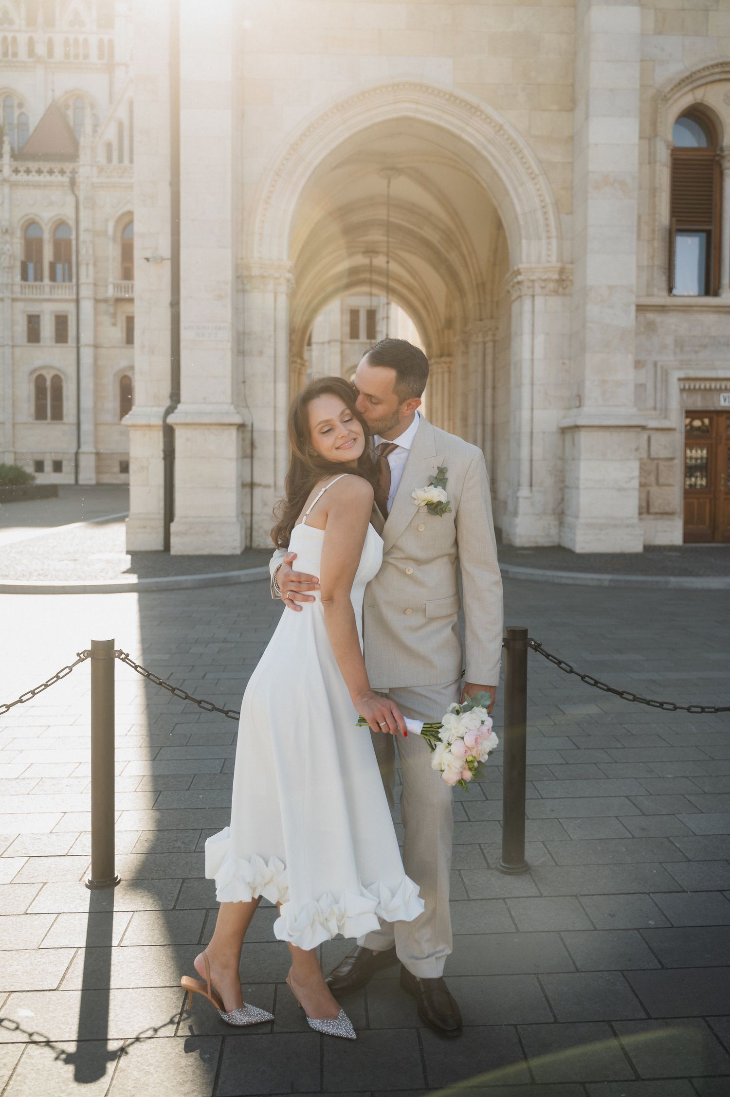 A tender moment between newlyweds captured in golden sunlight by historic architecture.