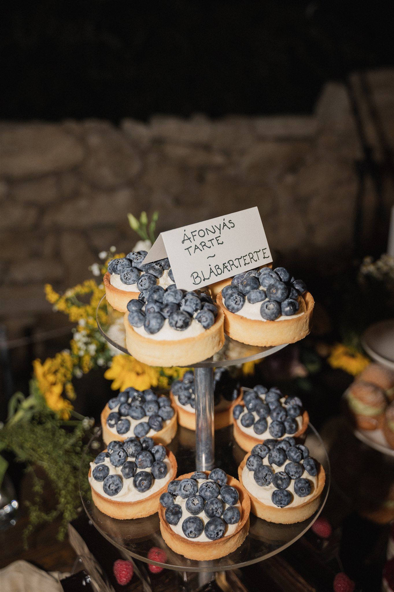 Elegant dessert display featuring mini tarts topped with fresh blueberries on a tiered stand.