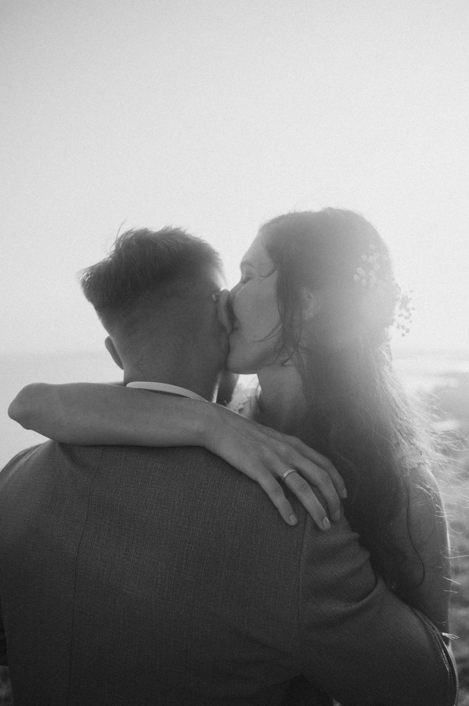 A romantic black and white sequence of a couple embracing and kissing in silhouette against a bright background.