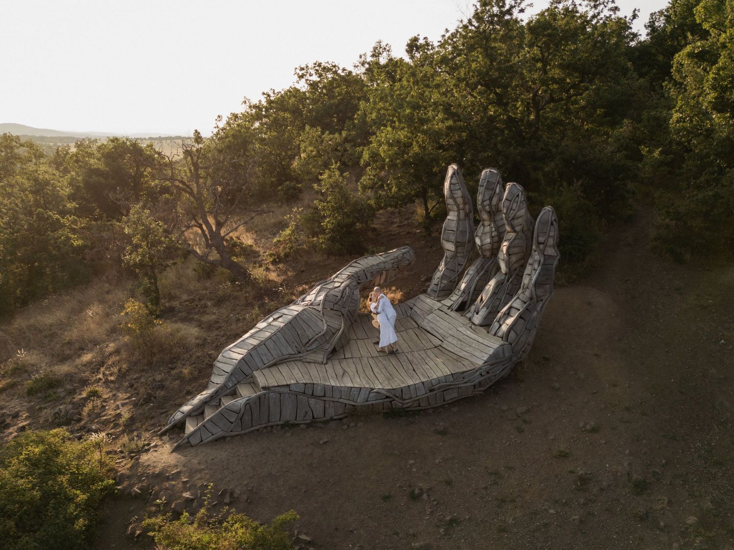 A large sculptural dragon installation winds along a hillside path in a natural outdoor setting.