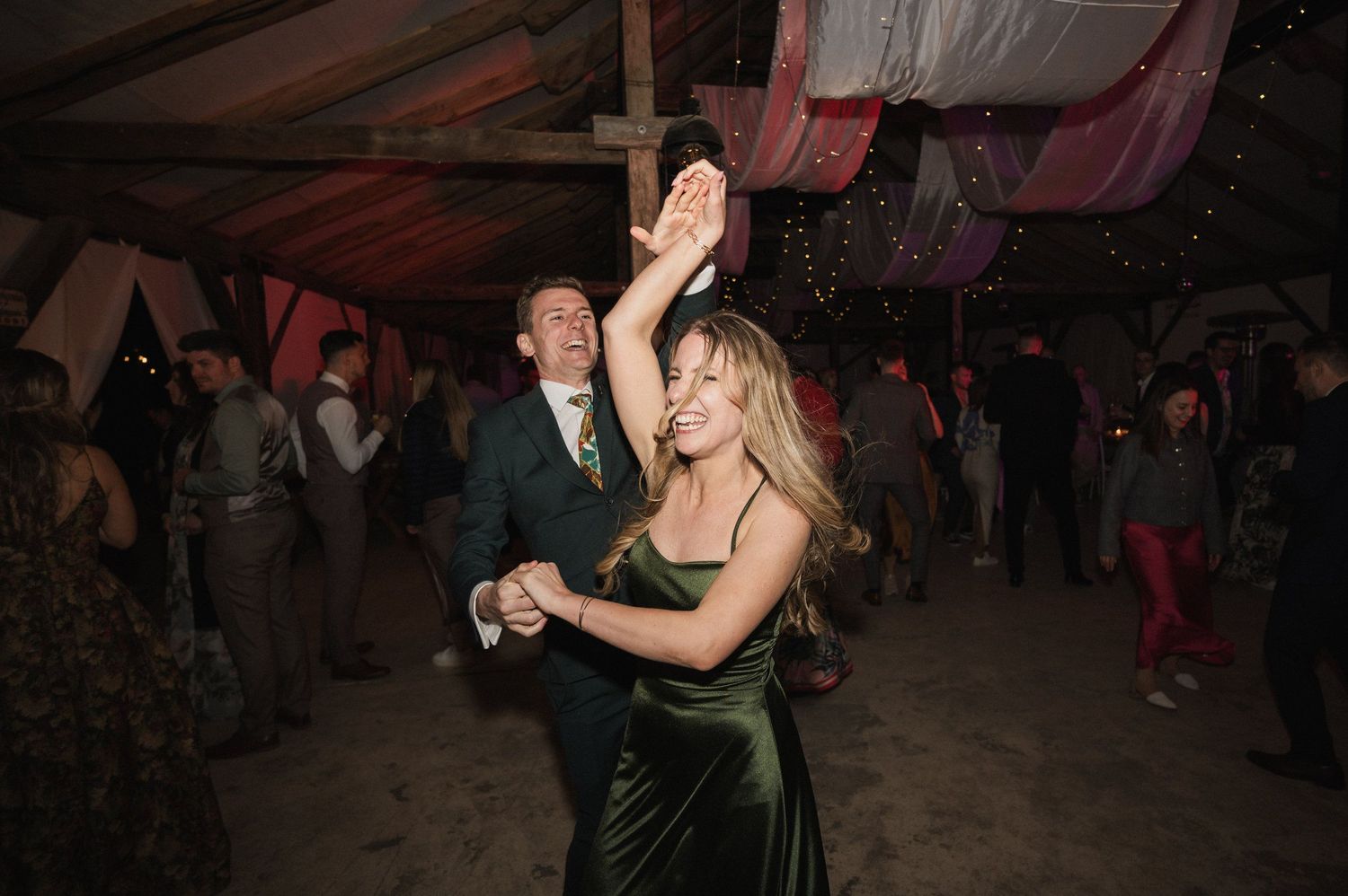 Couples dance together on a dimly lit dance floor at what appears to be a formal evening event.