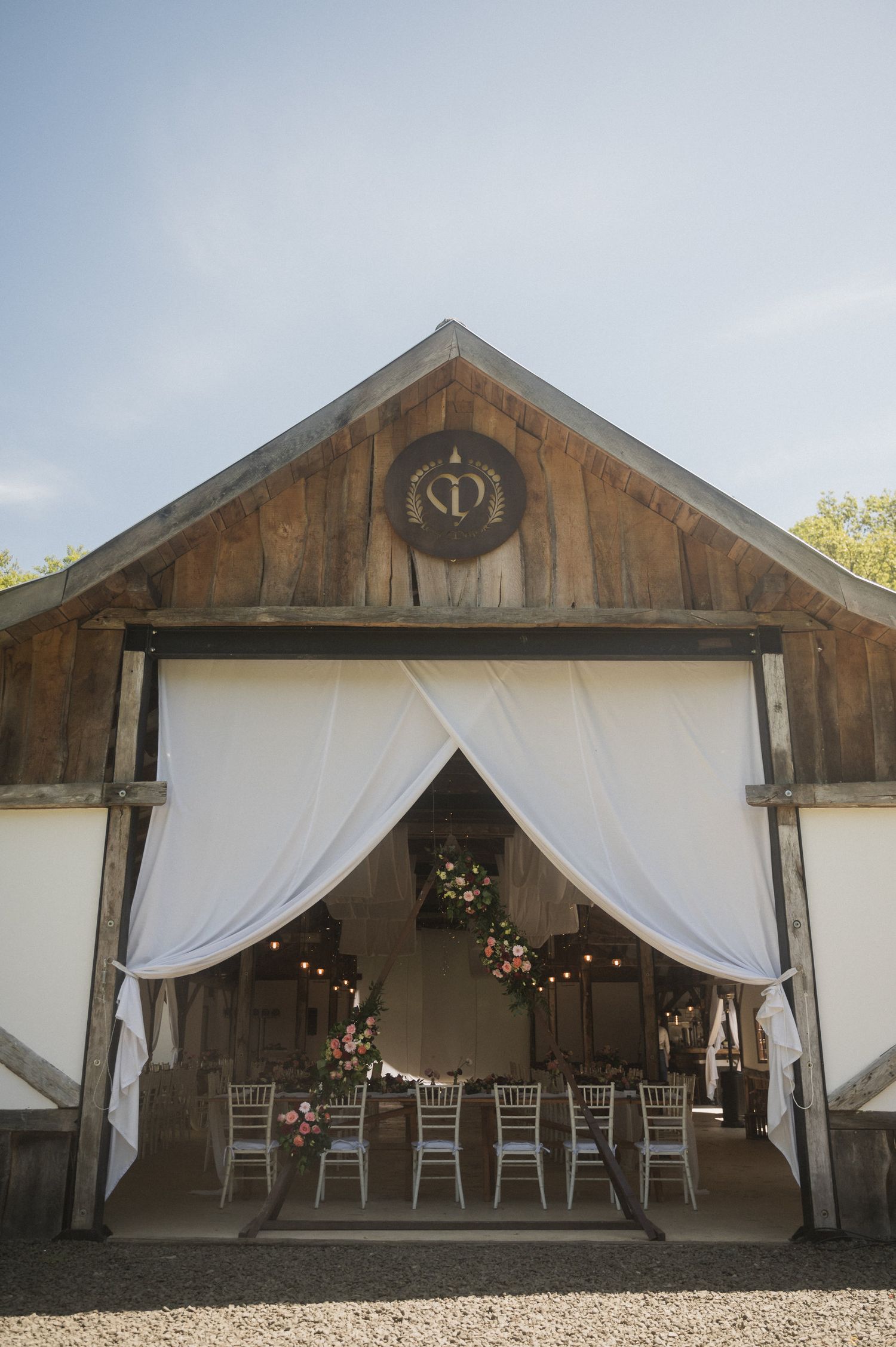Rustic barn wedding venue with white draping, string lights, and wooden beams creating an elegant atmosphere.