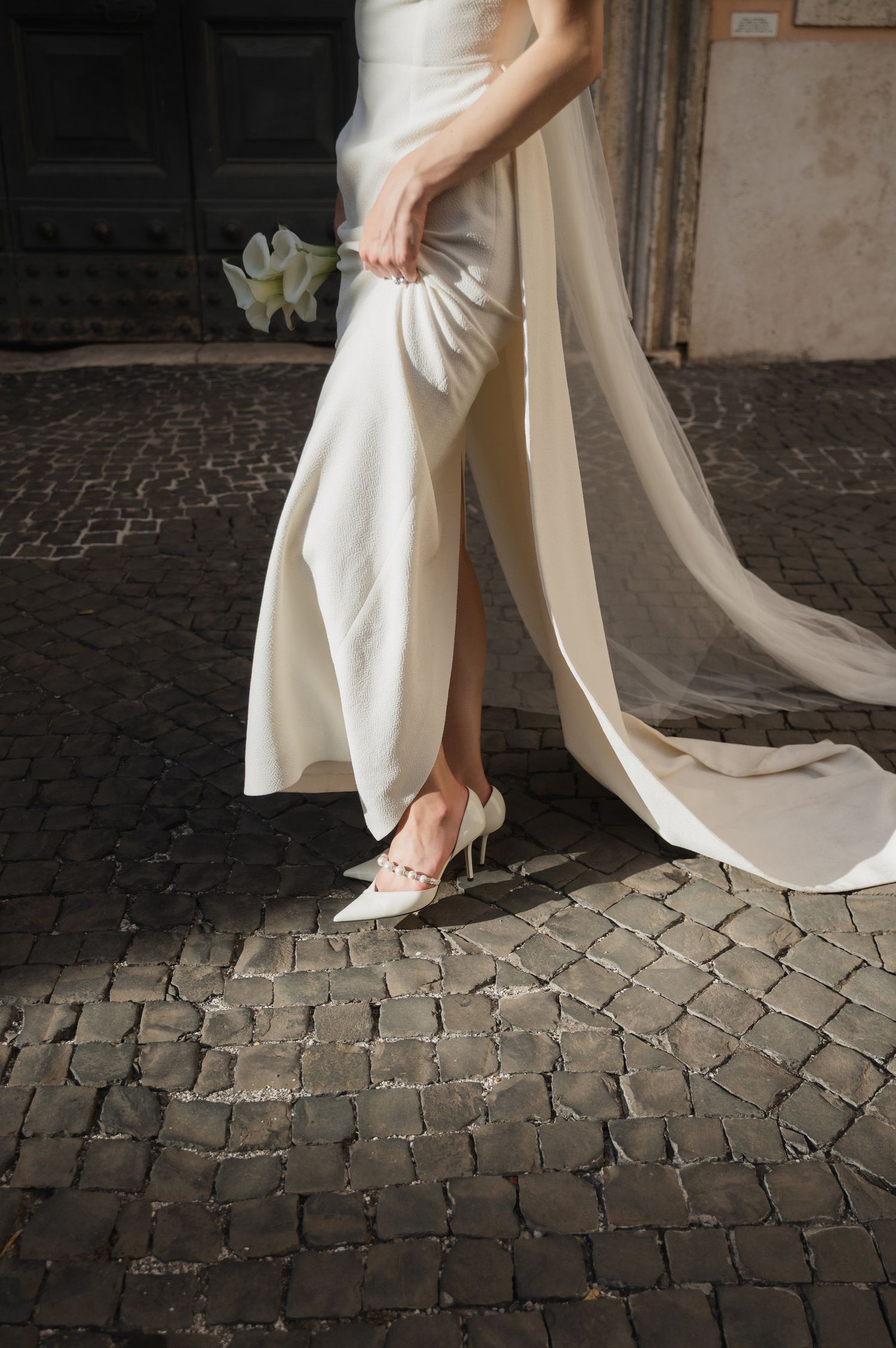 Wedding dress hem and heels on vintage cobblestone street.