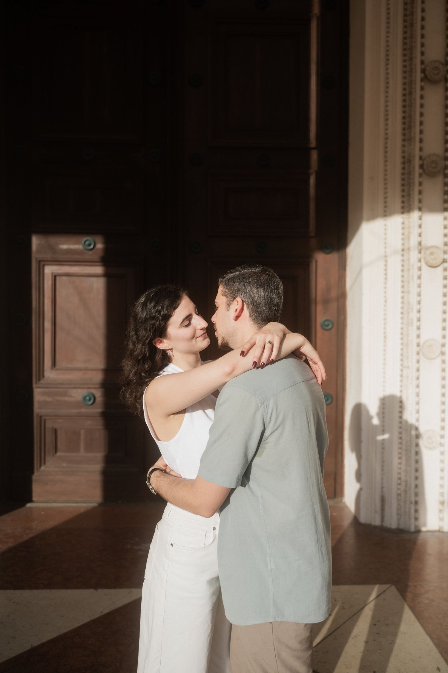 A tender moment captured between a couple in an elegant indoor setting with dramatic lighting.
