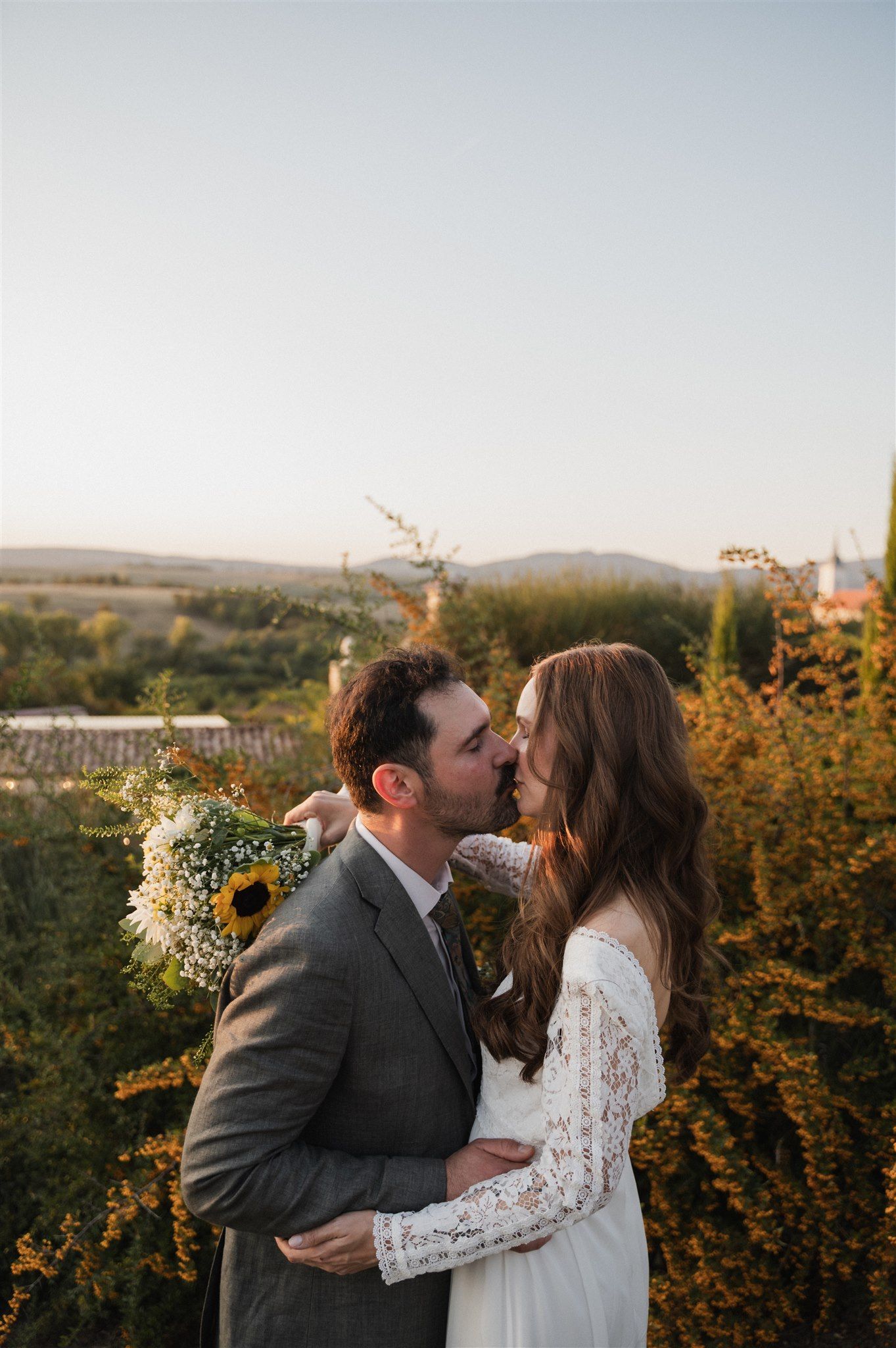 Couple sharing an intimate moment against a backdrop of autumn foliage at sunset.