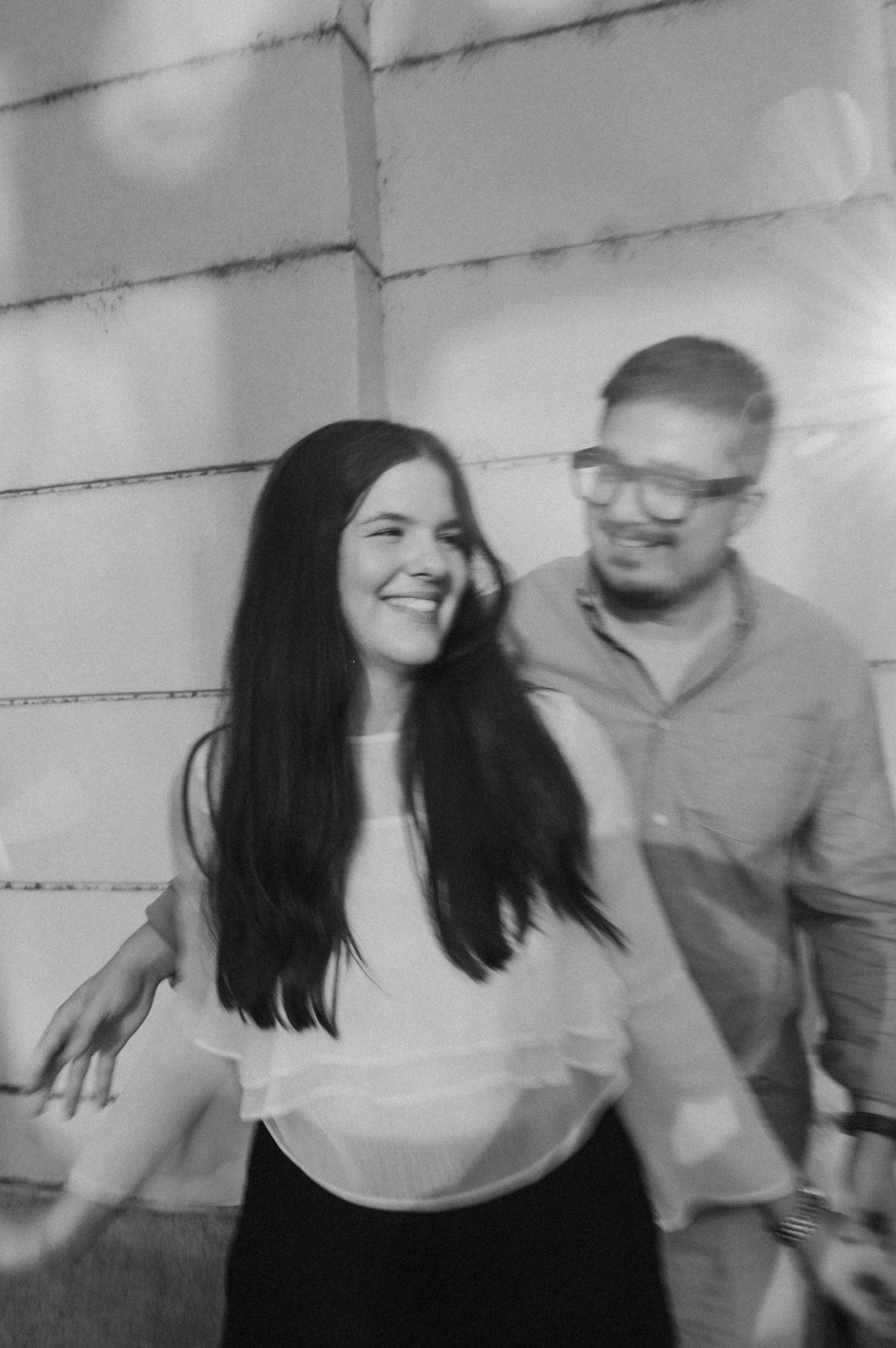 A joyful couple laughing and dancing together in a casual indoor setting.