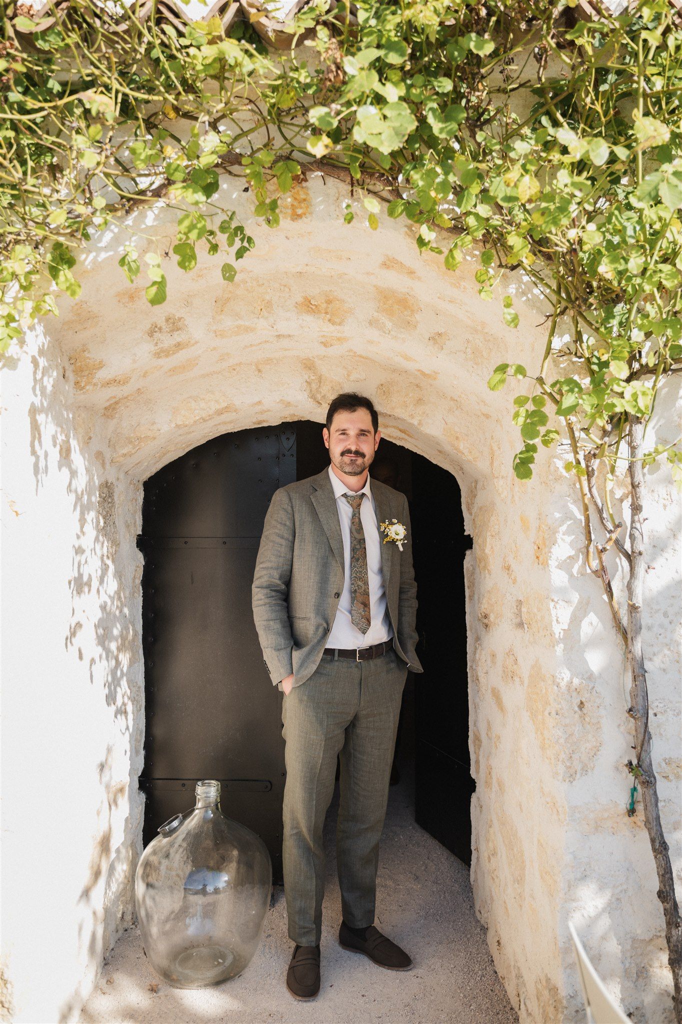 Stone archway with climbing vines creates romantic setting for wedding photos.