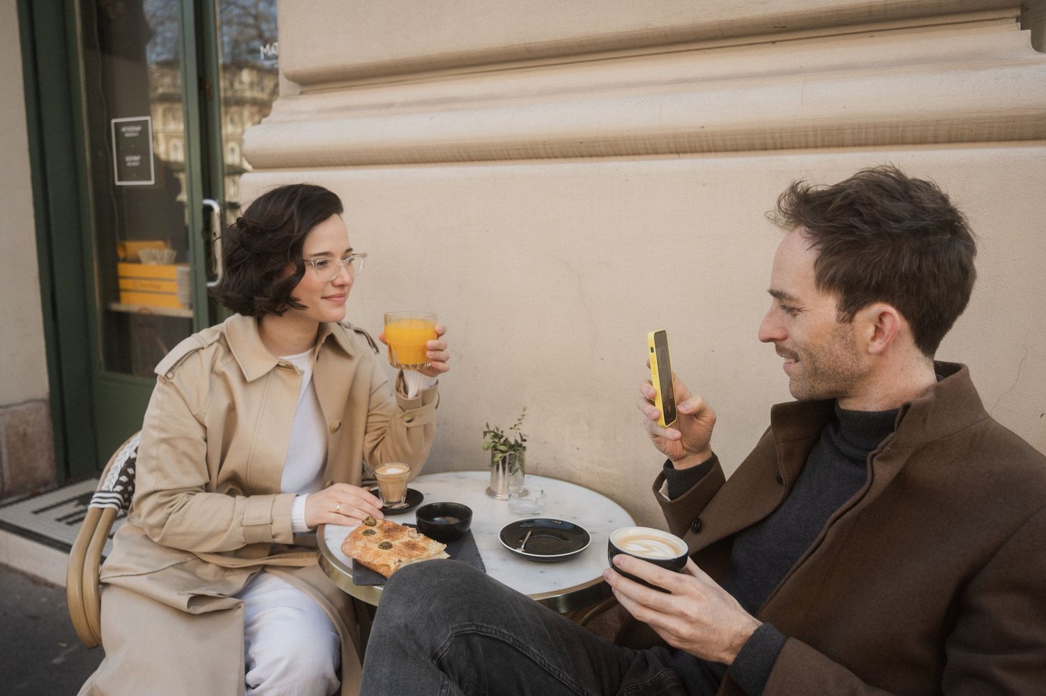 Friends enjoying drinks and conversation at an outdoor cafe table on a sunny afternoon.