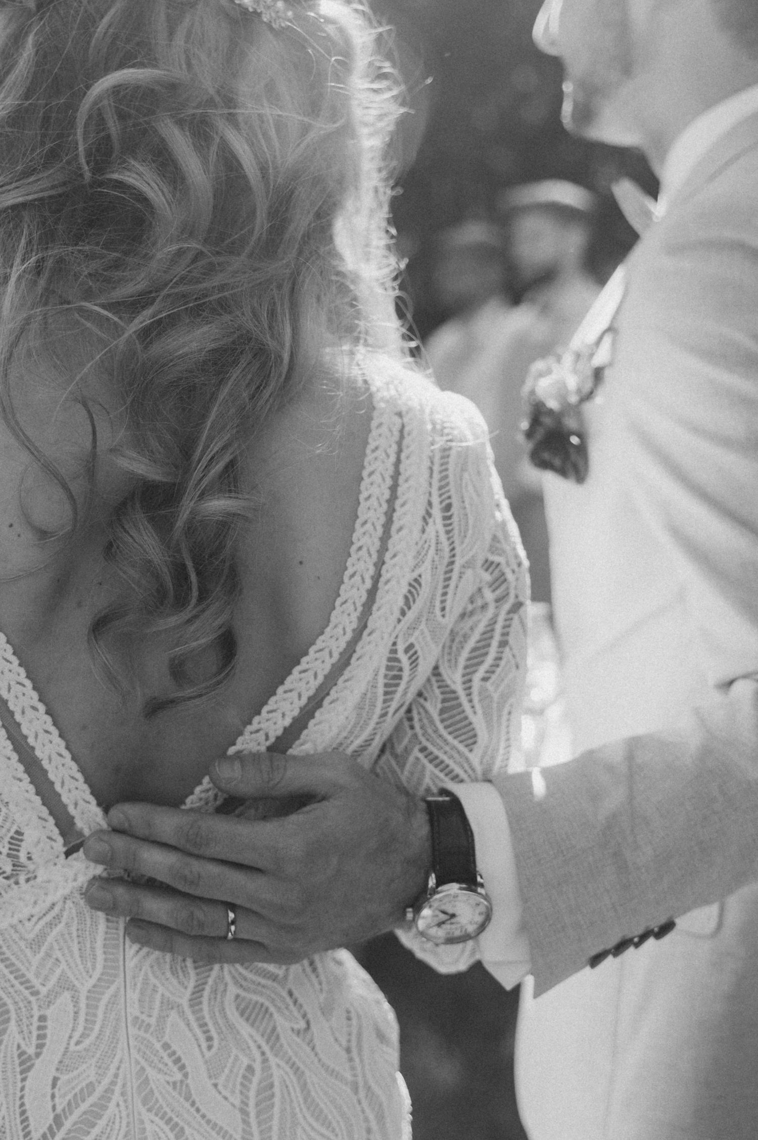Close-up black and white photo showing intricate lace details of a wedding dress during an intimate dance moment.