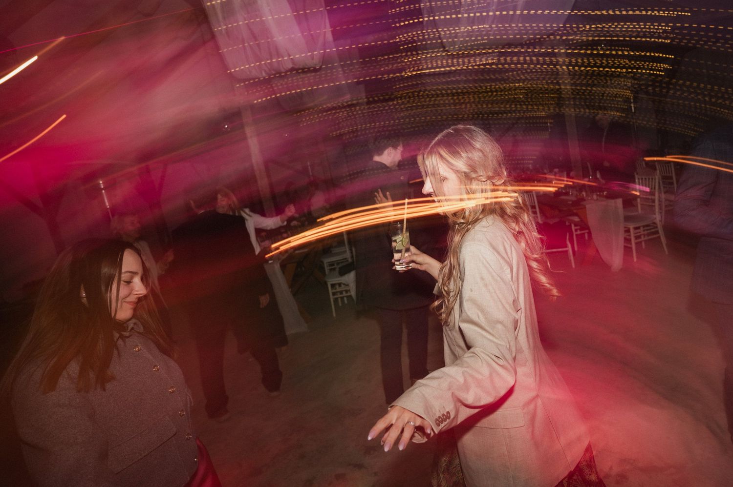 Long exposure photo of a person dancing at a nightclub with pink lighting and motion blur effects.