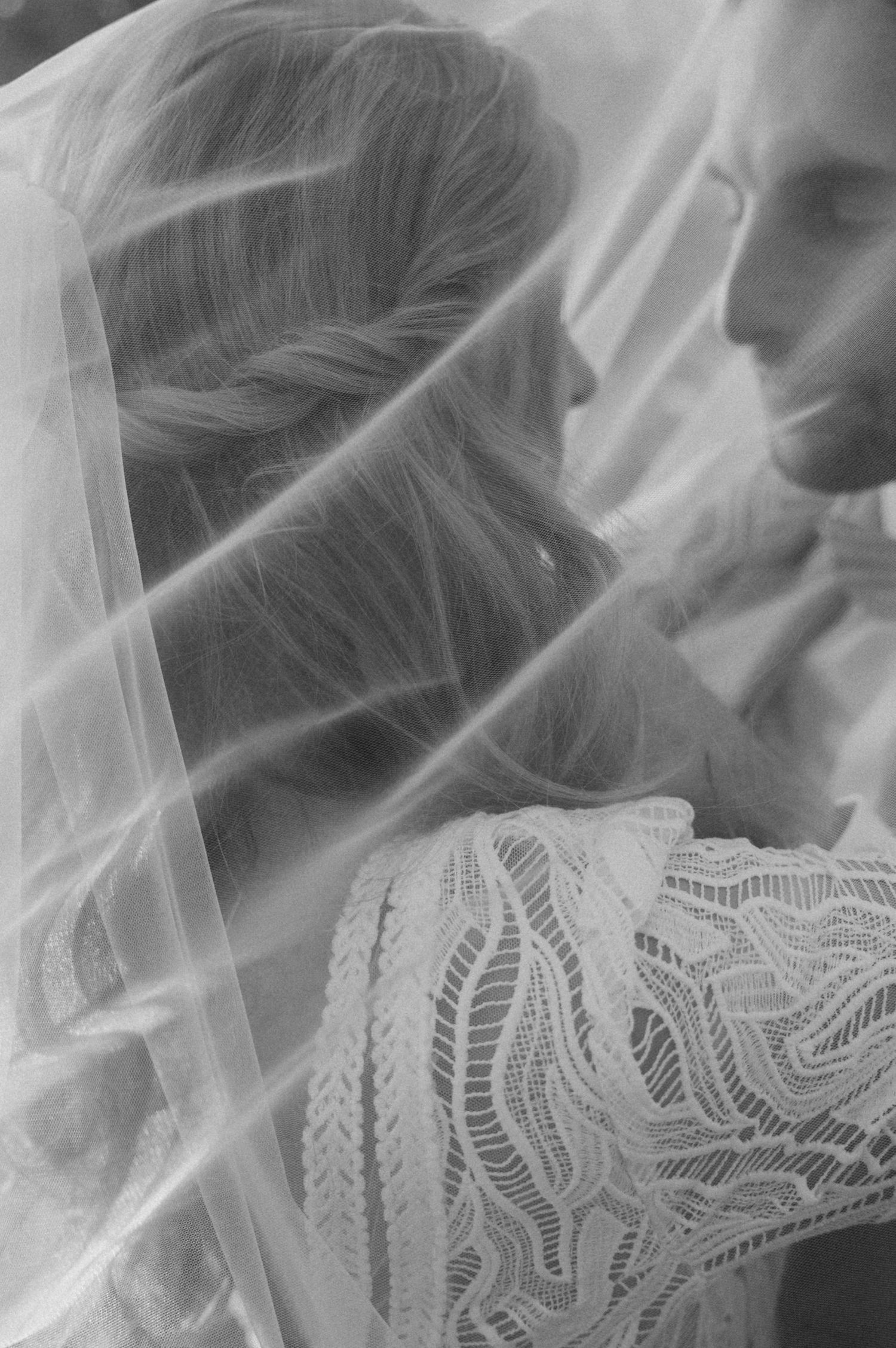 Close-up black and white detail of delicate lace wedding veil with intricate pattern work.