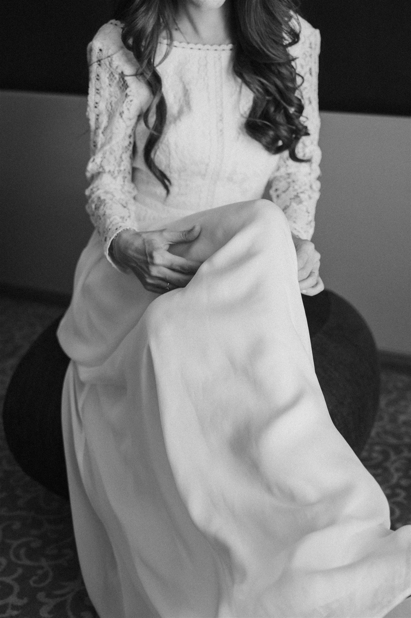 A close-up detail shot of a white lace wedding dress with long sleeves.