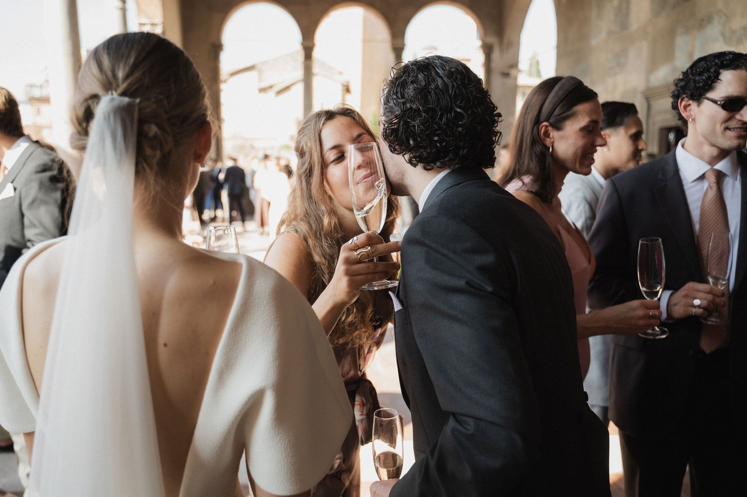 Wedding guests mingle and socialize in an elegant columned venue during a reception.