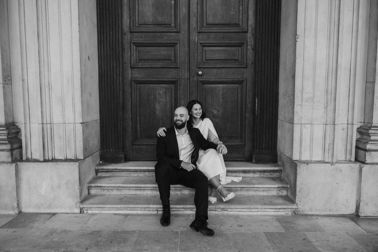 Artistic sequence of newlyweds creating dramatic poses against historic building entrance.
