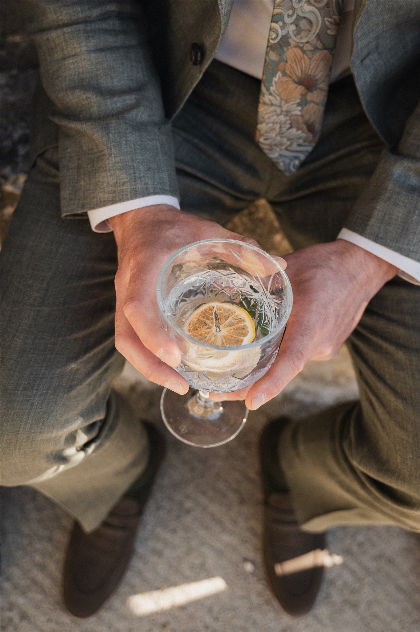 Close-up shot of hands holding a cocktail glass with a citrus garnish.