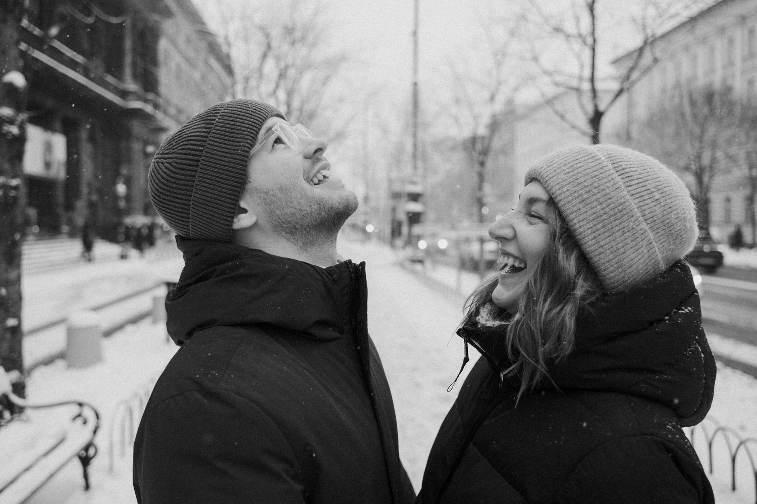Two people share a lighthearted moment laughing together in the snow.