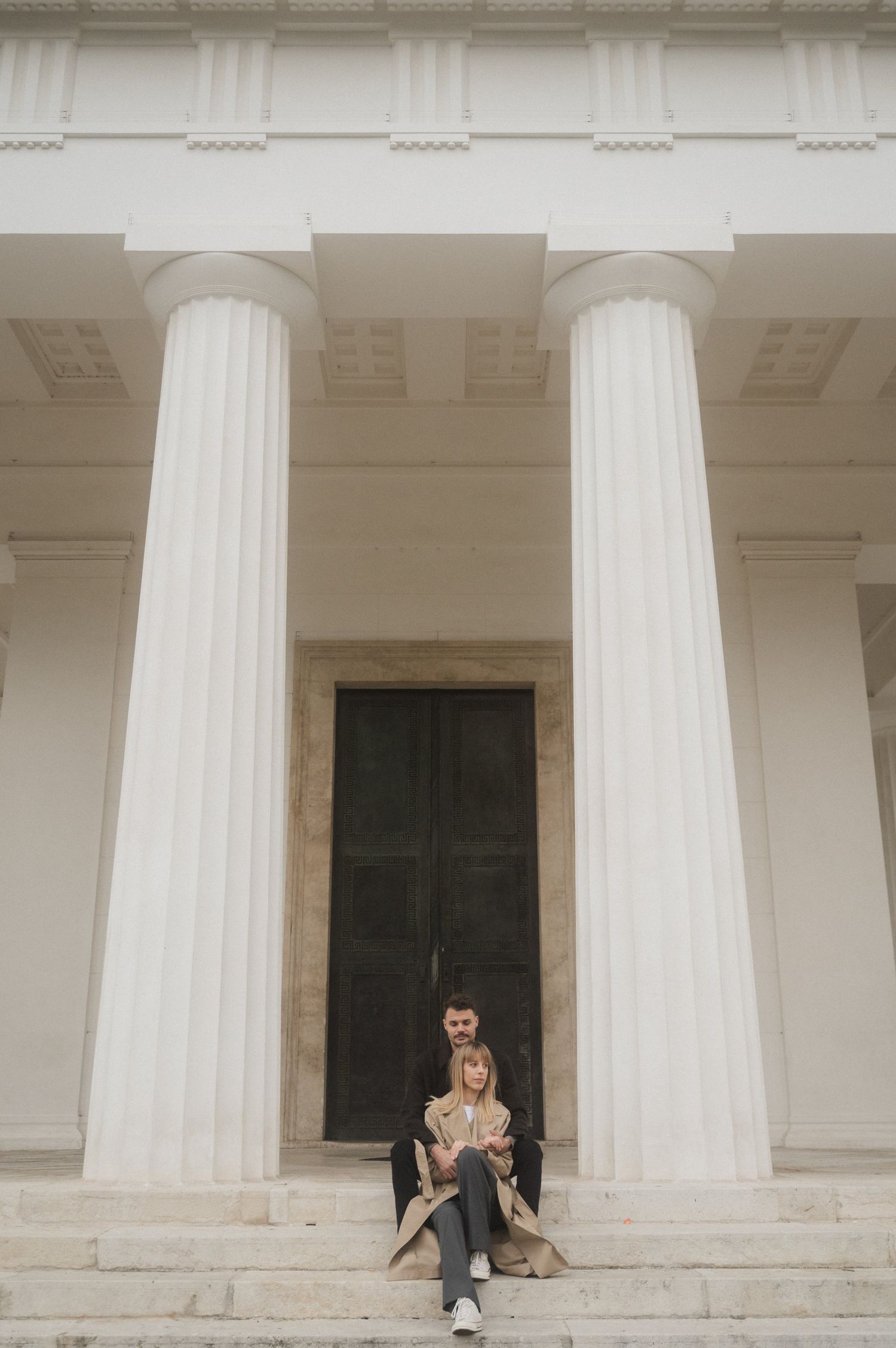 Four sequential photos show a person sitting between white classical columns on a building's stone steps.