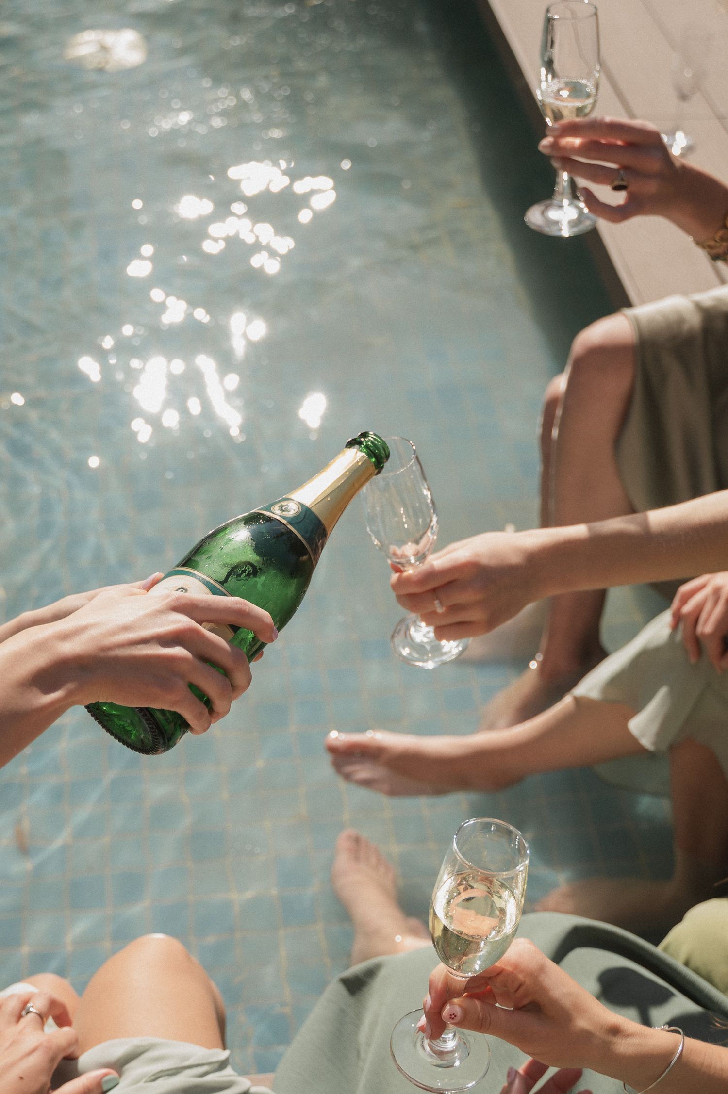 Sequence showing hands pouring and serving champagne into elegant glasses by a pool with sparkling water reflections.