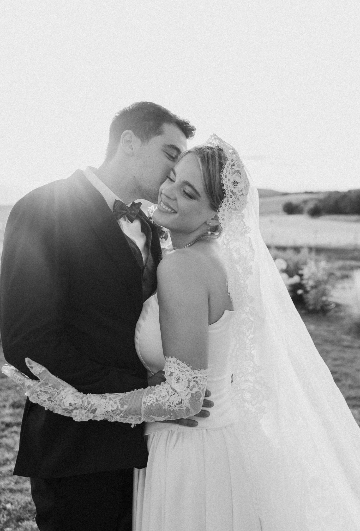 Romantic black and white wedding portraits of couple embracing outdoors.