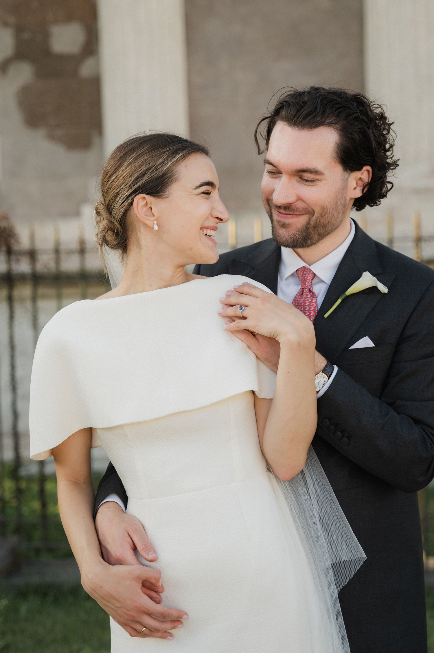 Wedding couple shares playful and romantic moments in front of a stone wall.