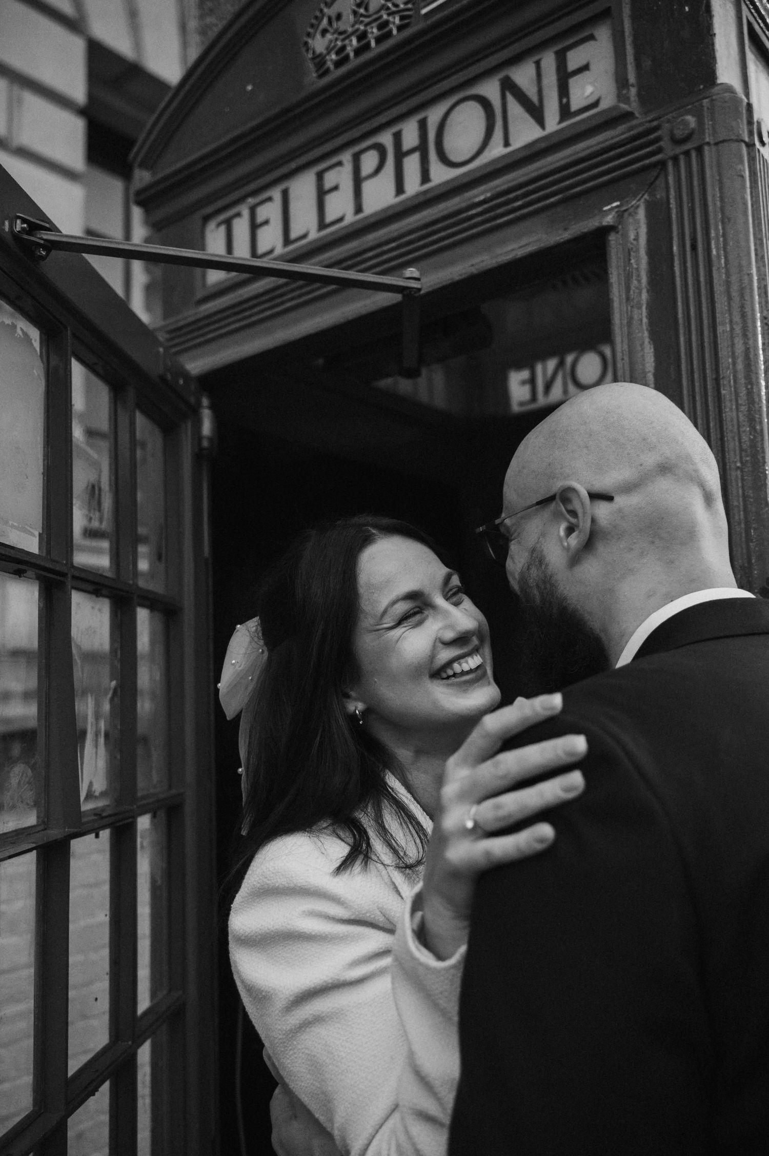 A joyful moment captured in black and white inside a London telephone booth.