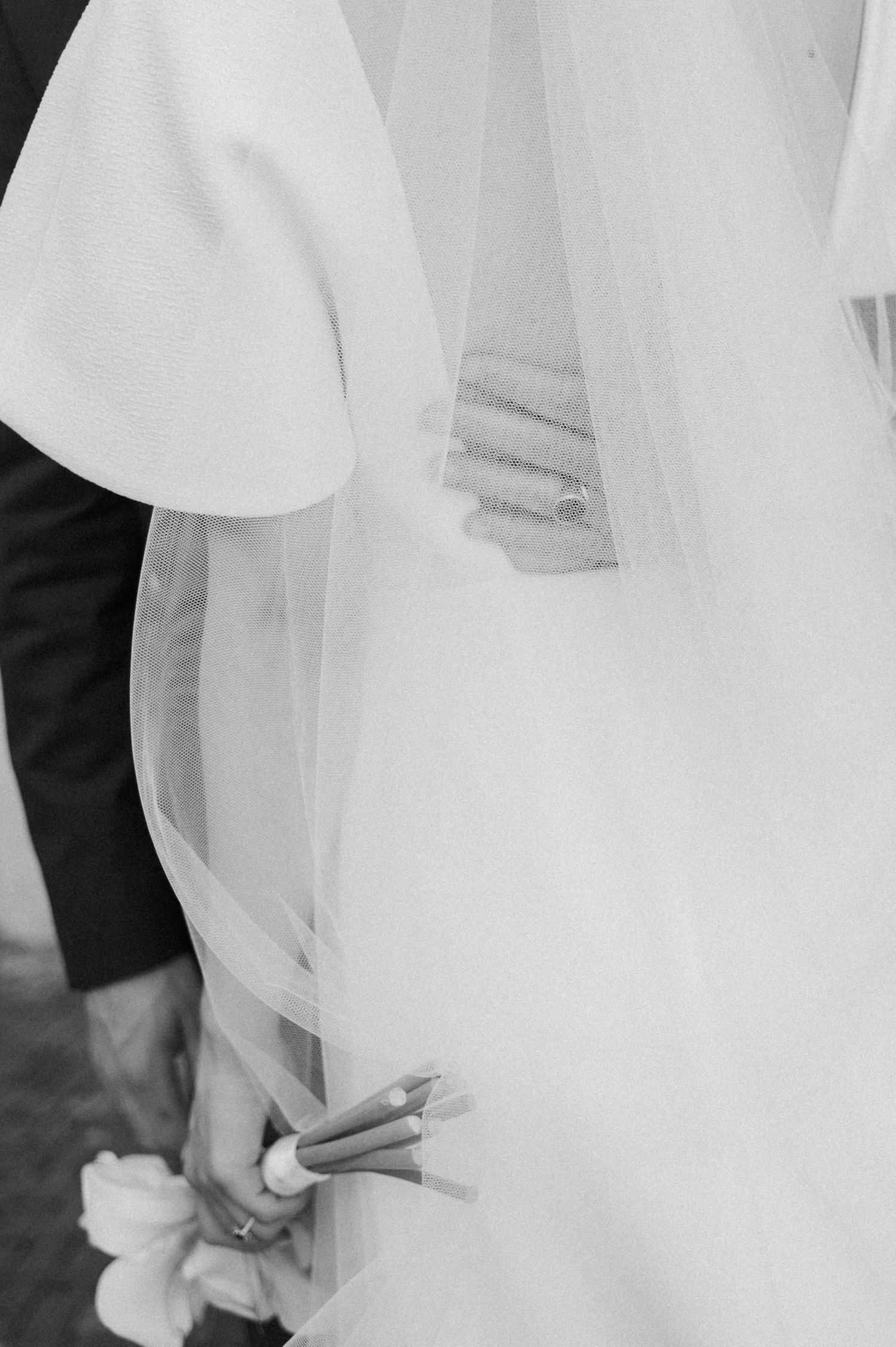 Close-up detail of flowing white wedding dress fabric against cobblestones.
