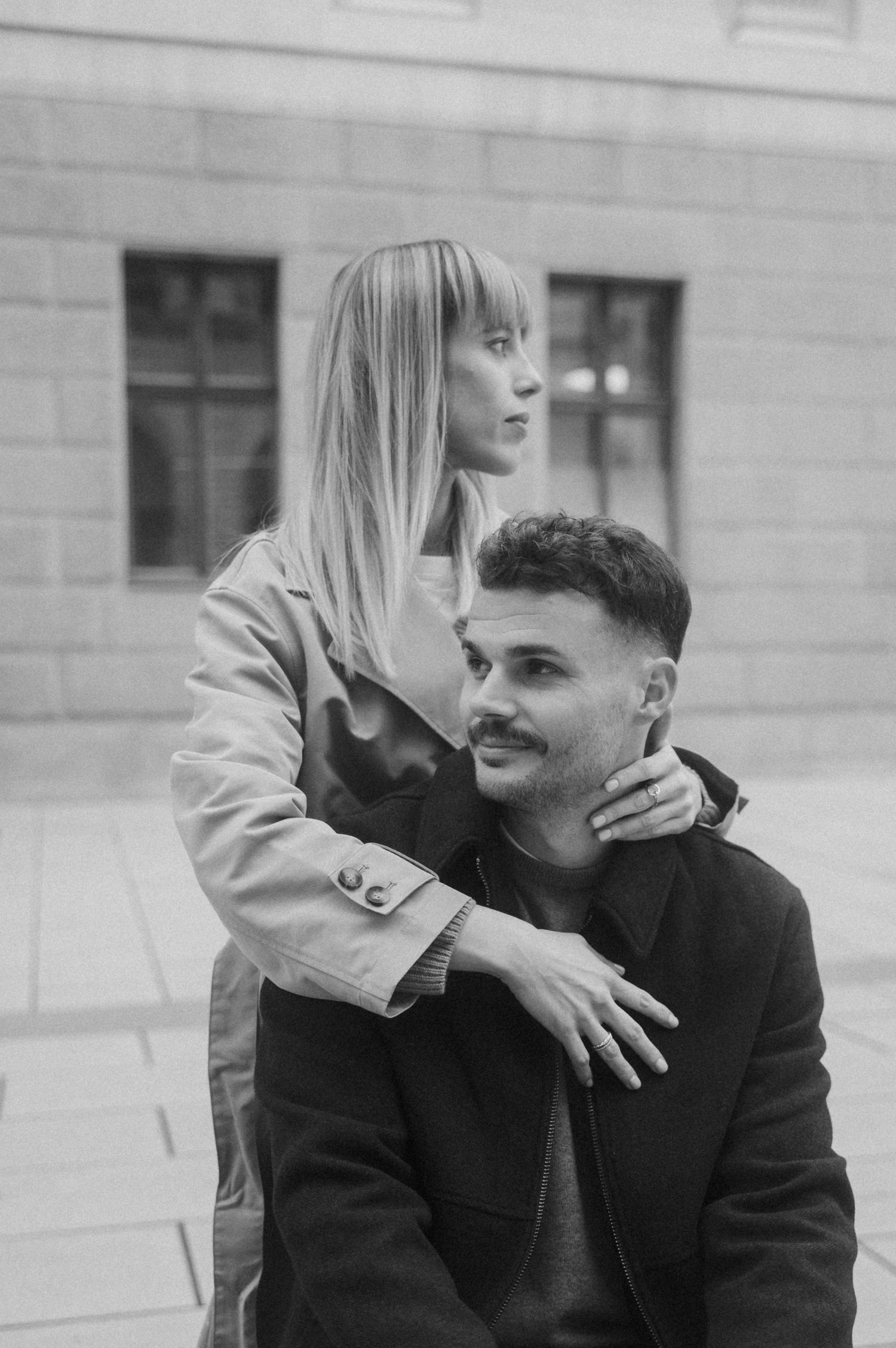 A romantic black and white photo sequence showing a couple embracing and sharing intimate moments against a building wall.