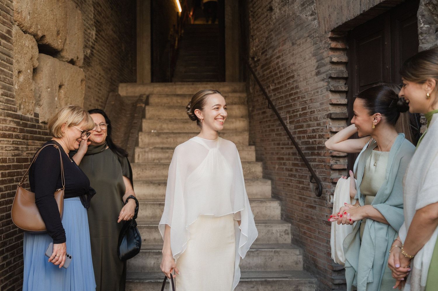 Wedding party members gathered on historic stone steps in formal attire.