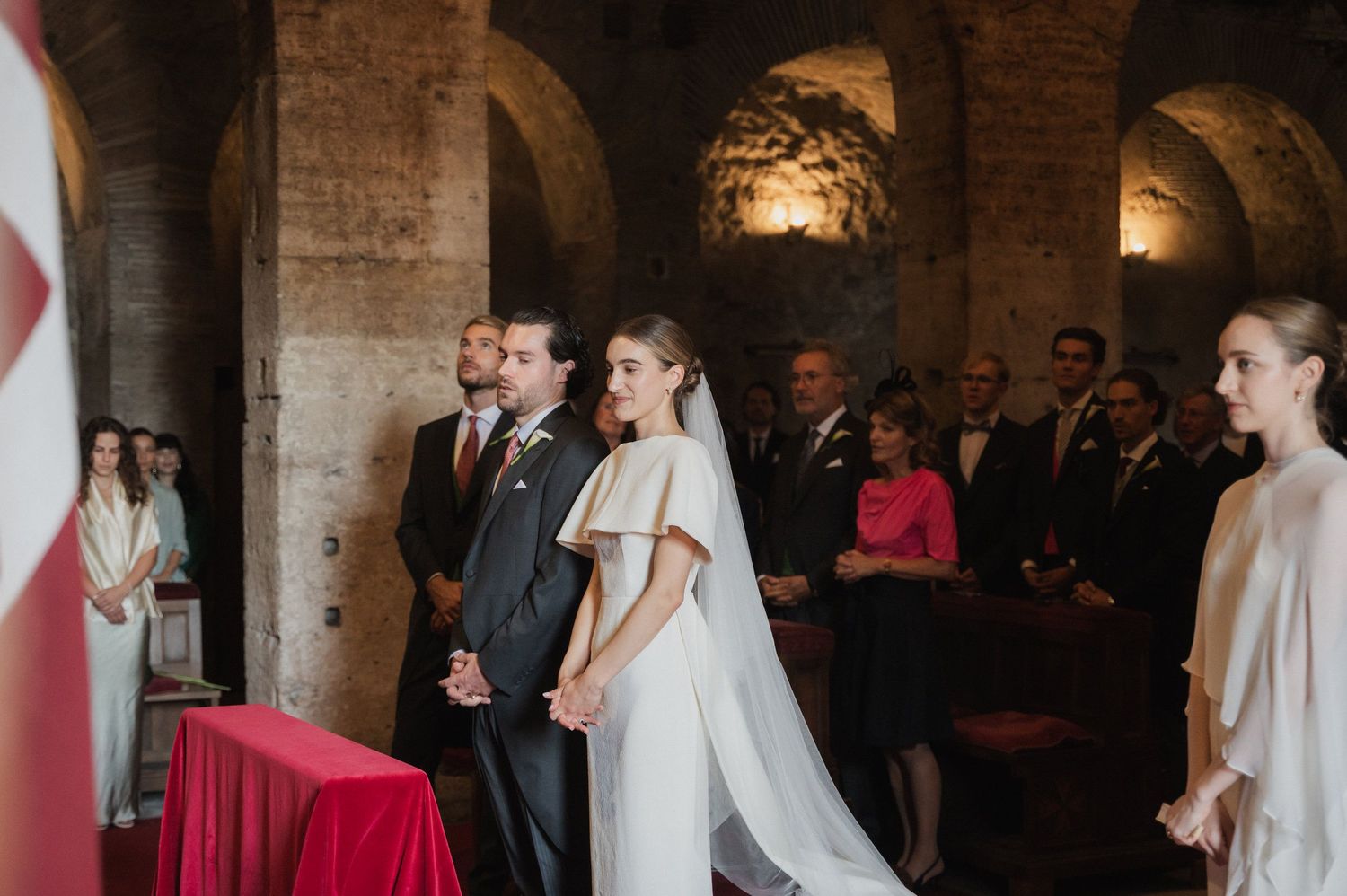 Wedding ceremony in historic brick venue with dramatic arched ceilings and red decor.