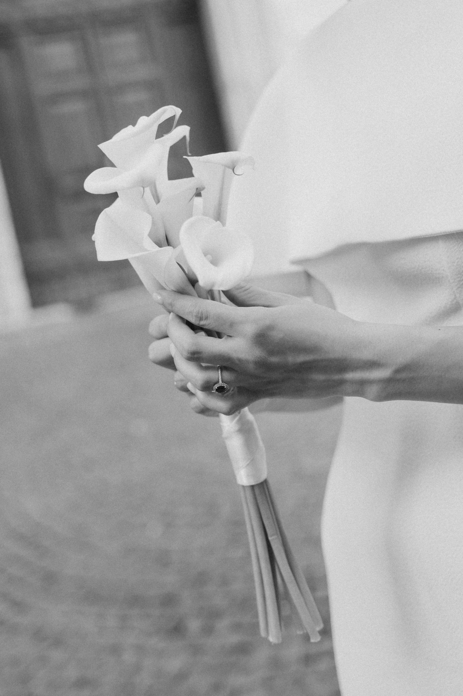 Black and white photo of a delicate calla lily wedding bouquet wrapped in white ribbon.