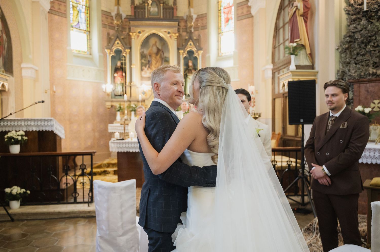 Bride and groom share a tender moment at the altar of a decorated church.