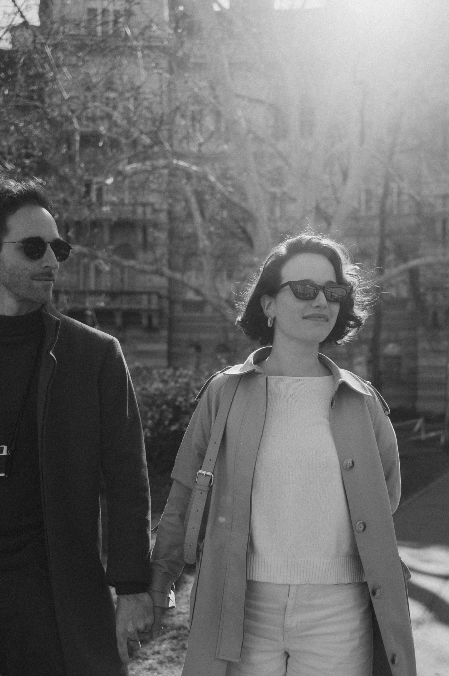 A sequence of black and white photos showing two people walking together in a park on a sunny day.