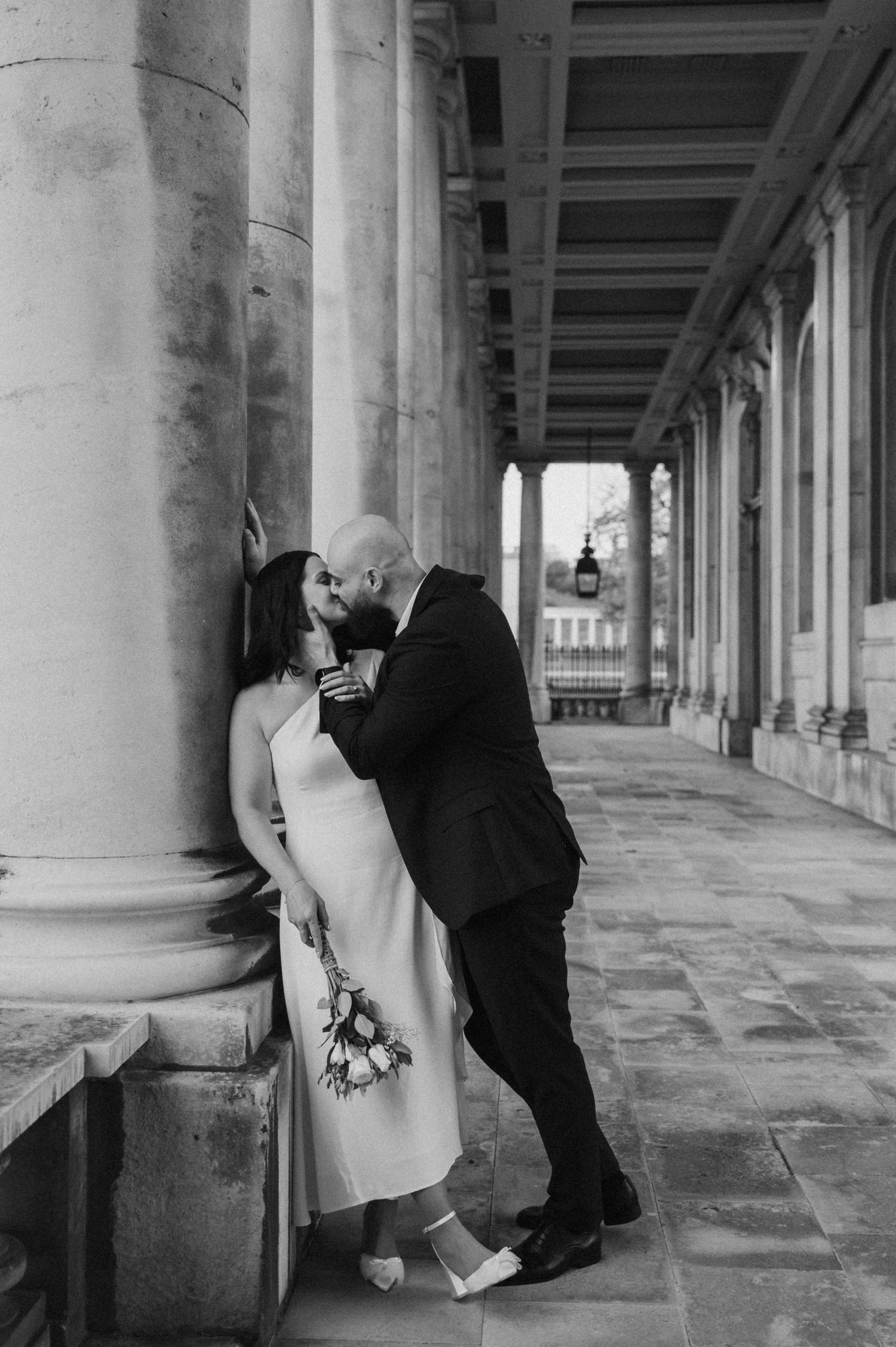 A romantic black and white moment captured between a couple in an elegant colonnade setting.