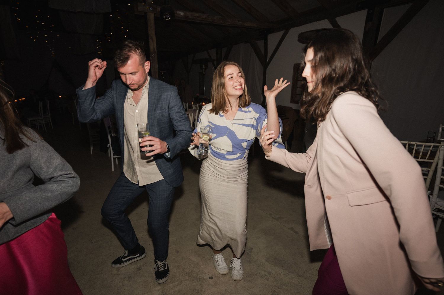 A group of people dancing and socializing in a dimly lit space during what appears to be a party or celebration.