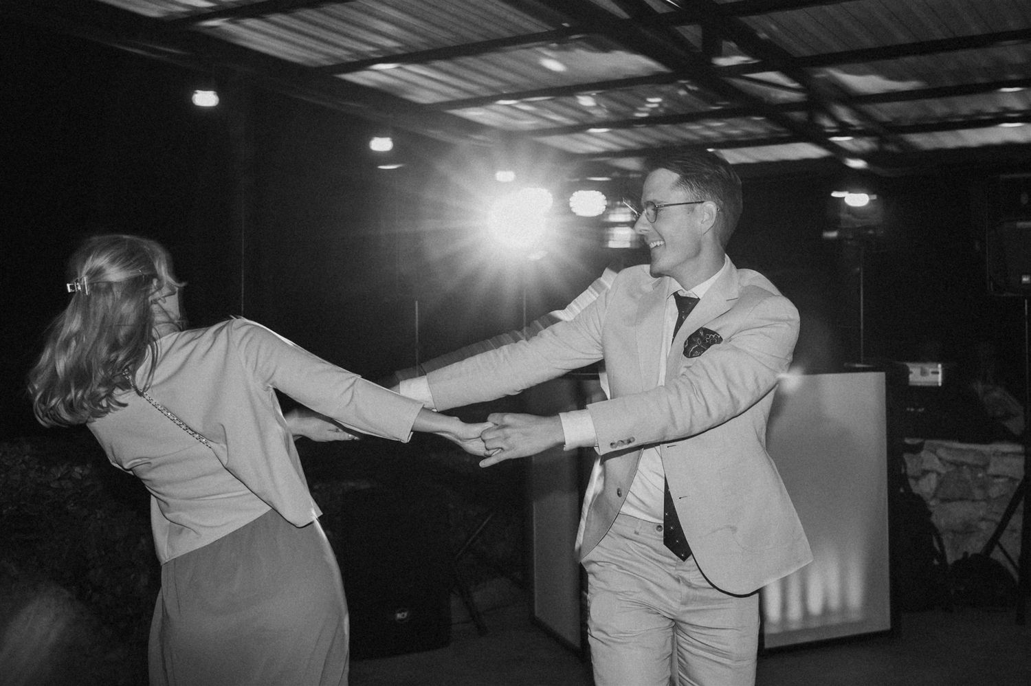 Black and white photos of wedding guests dancing energetically at a covered venue.