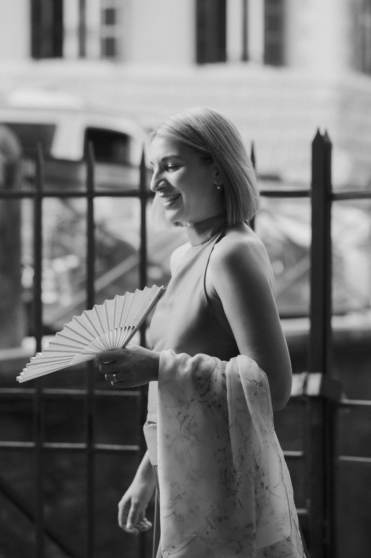 Artistic black and white photo of a figure with a decorative fan in elegant attire.