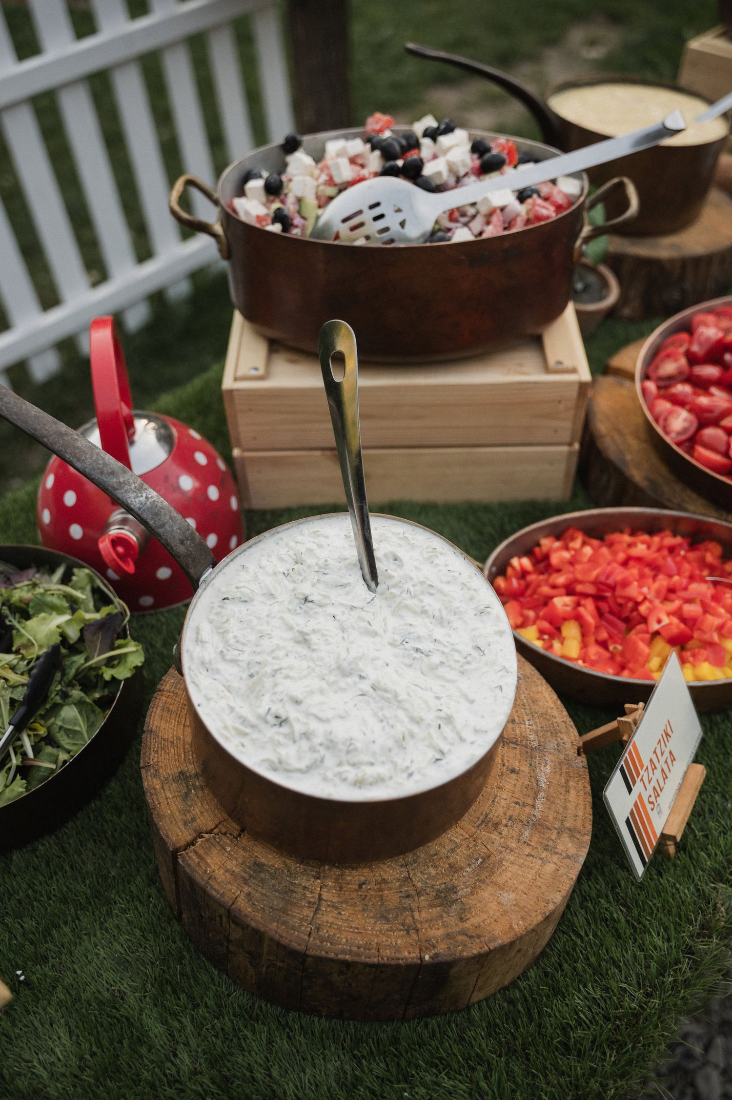 Rustic outdoor buffet setup with dips, fresh vegetables and decorative mushroom ornament on wooden surfaces.