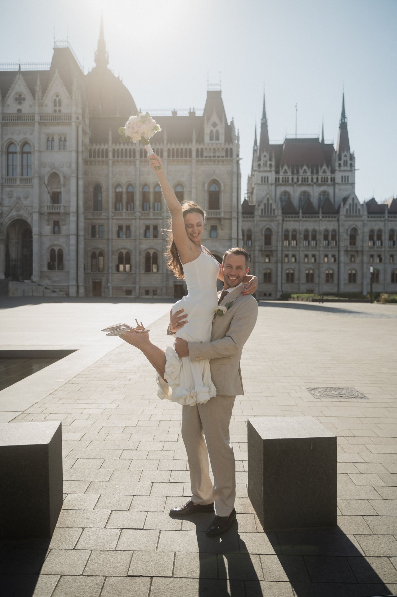 A celebratory dance pose captured in front of Budapest's historic Parliament building.