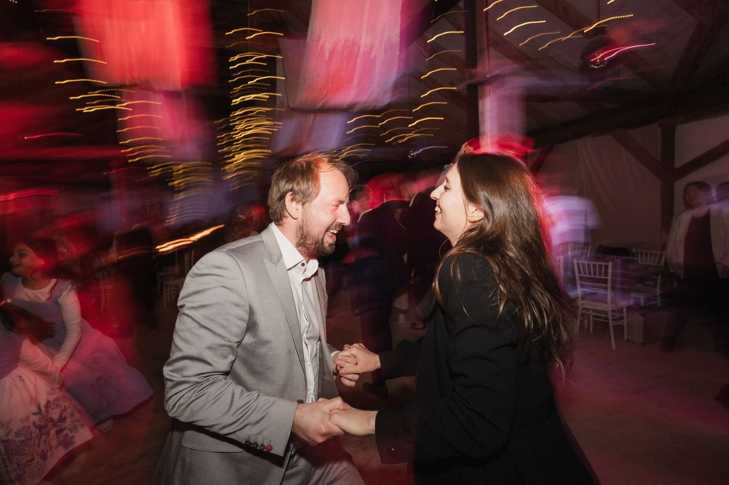 Couples dance together in a dimly lit venue with red lighting and motion blur creating a romantic atmosphere.