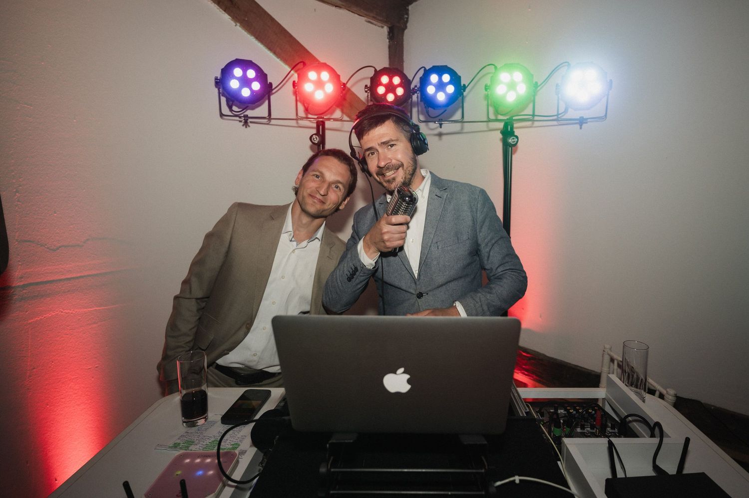DJ booth setup at an event with colorful LED lights illuminating the equipment and decor.