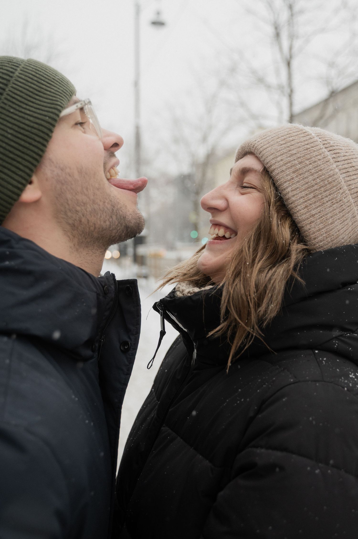 A playful winter moment shared between two people wearing beanies in the snow.