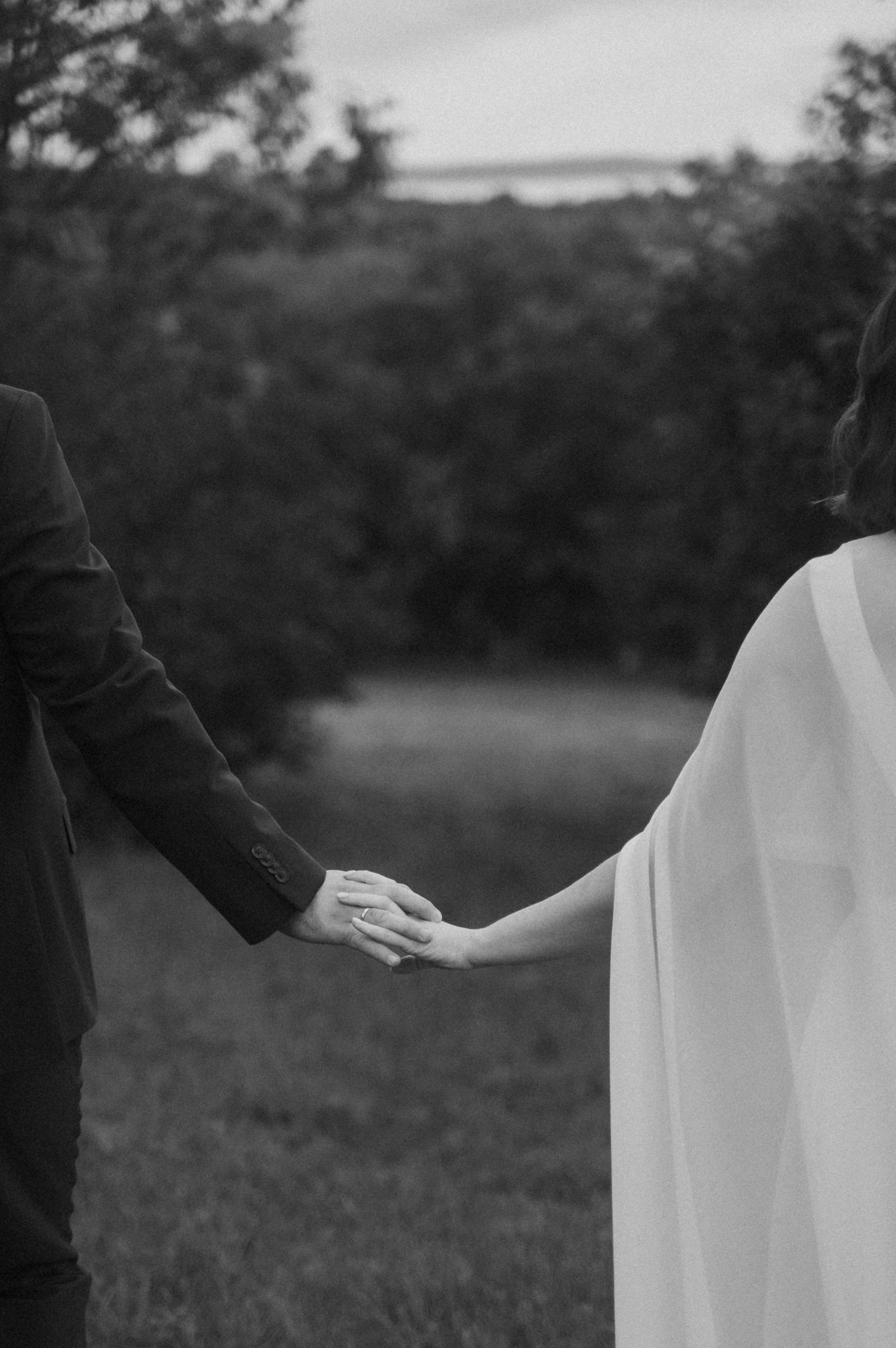 Black and white artistic photo series showing couple holding hands in a romantic outdoor setting at dusk.